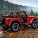 A red 2020 Jeep Wrangler is crossing a river in the mountains. See one at a Jeep dealer near me.