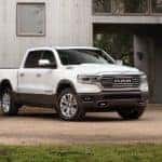 A white 2020 Ram 1500 Laramie Longhorn from a Ram dealer near me is parked in front of a metal building.