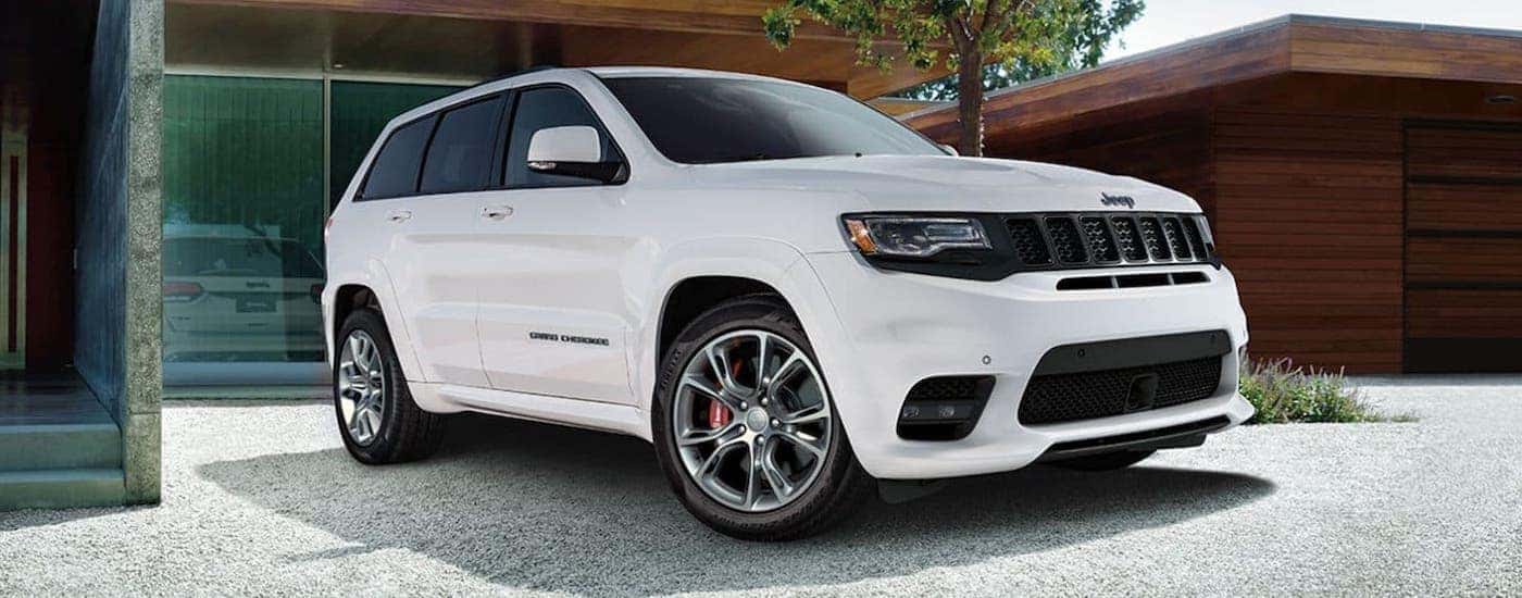 A white 2020 Jeep Grand Cherokee is parked in front of a house.