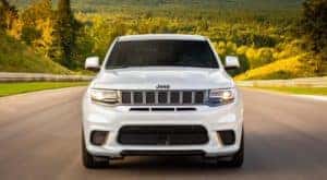 A white 2020 Jeep Grand Cherokee is shown on a race track from the front.