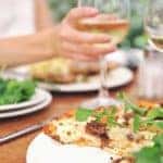 Wine, salad, and a flat bread pizza are on a table at an outdoor restaurant in Cincinnati, OH.