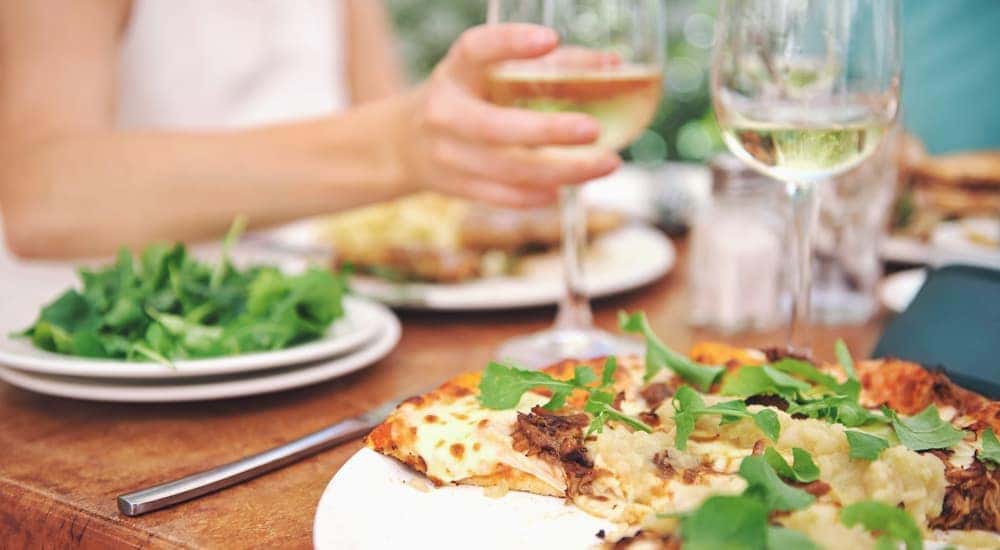 Wine, salad, and a flat bread pizza are on a table at an outdoor restaurant in Cincinnati, OH.