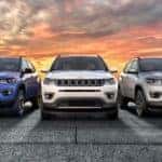 Three of the available Jeep models at your local dealer, a blue, a white, and a silver 2020 Jeep Compass are shown from the front at sunset.