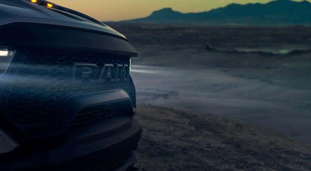 A closeup shows the grille on a 2021 Ram TRX that is parked in a desert at dusk.