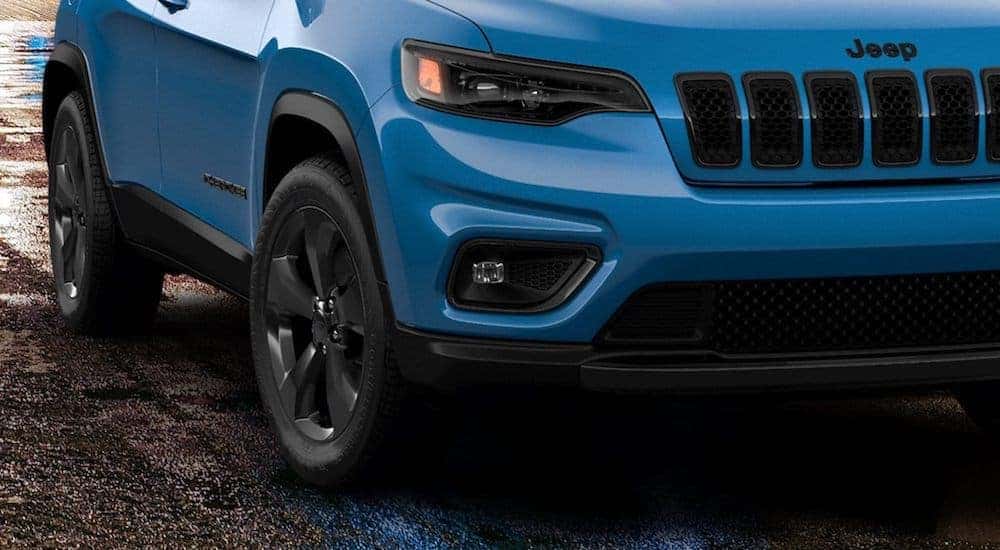 A blue 2020 Jeep Cherokee Latitude is parked on wet street.
