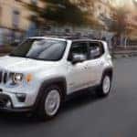 A popular Jeep SUV, A white 2021 Jeep Renegade Limited is driving down a blurred city street.