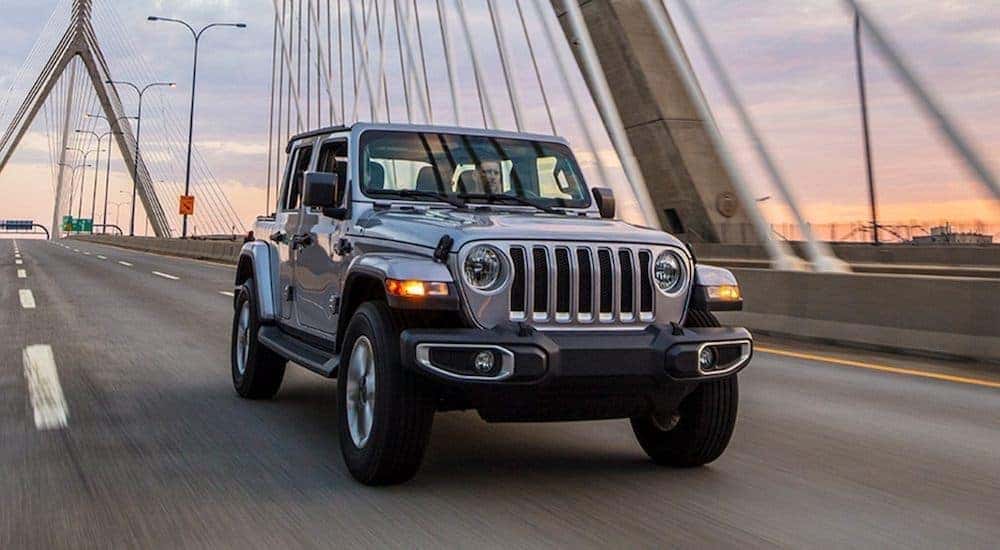 A silver 2021 Jeep Wrangler Unlimited is driving over a bridge.