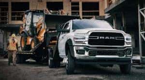 A worker is next to a white 2020 Ram Chassis Cab truck in a construction area.