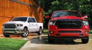A white 2020 Ram 1500 and a red 1500 Classic are parked in front of a barn after leaving a Cincinnati Ram diesel truck dealer.