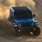 A blue 2021 Jeep Wrangler Rubicon 392 is off-roading in sand.