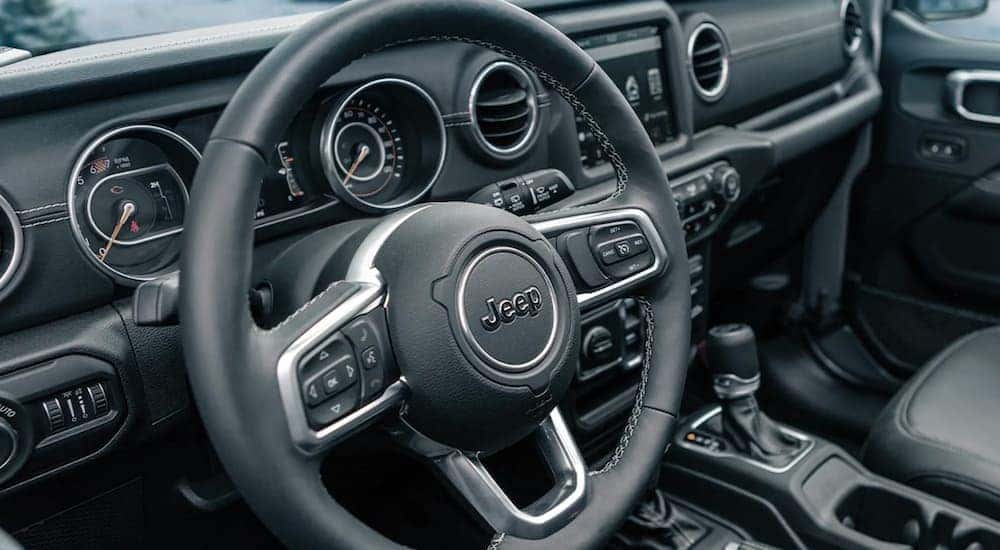The black interior and steering wheel is shown on a 2021 Jeep Wrangler.