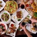 A table with food and hands holding drinks is shown from above in Burlington, KY.