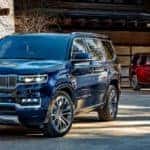 A blue and a red 2022 Grand Wagoneer are parked in front of a modern cabin.