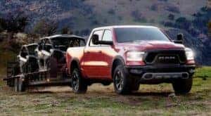 A red 2021 Ram 1500 is towing a trailer with side-by-sides off-road after leaving a Ram dealer near Covington.