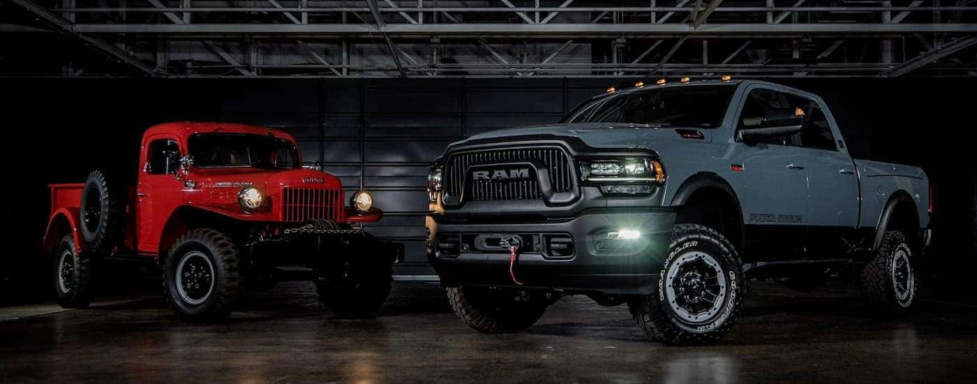 A grey 2021 Ram 2500 Power Wagon is parked next to a red 1954 Power Wagon in a warehouse.