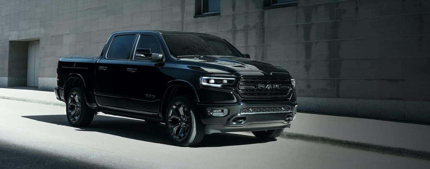 A black 2021 Ram 1500 is shown from the side parked in front of a concrete building.