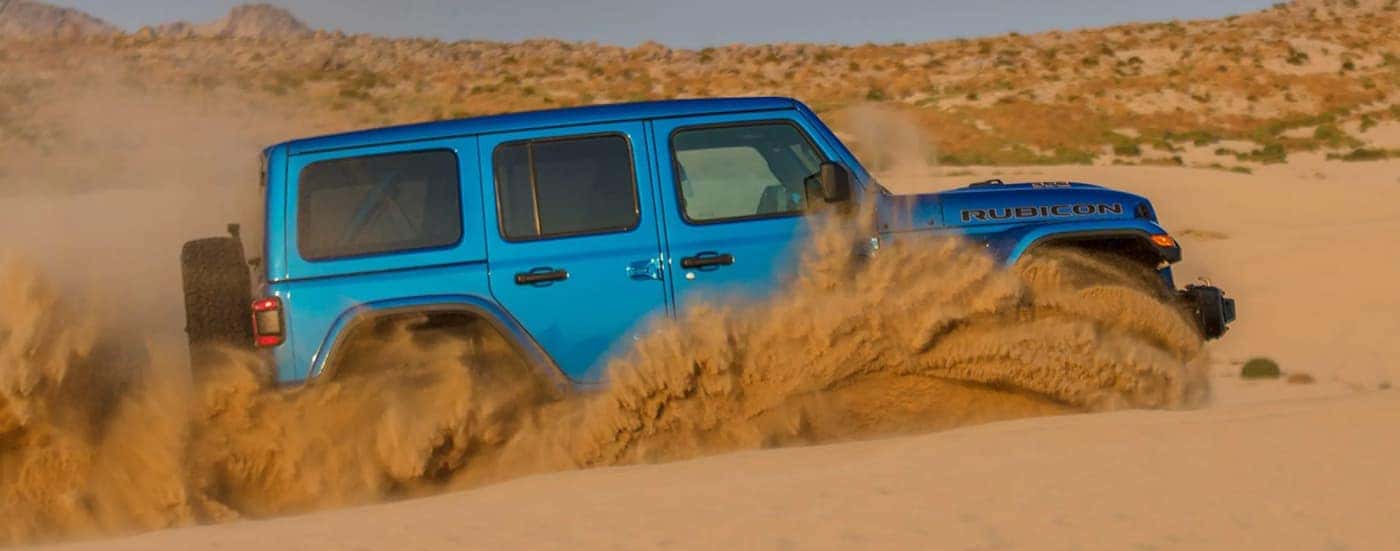 A blue 2021 Jeep Wrangler Rubicon 392 is shown from the side off-roading in the desert.
