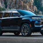 A black 2022 Grand Wagoneer is shown from the side parked in front of a rock face.
