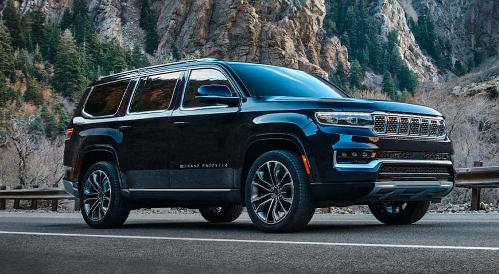 A black 2022 Grand Wagoneer is shown from the side parked in front of a rock face.