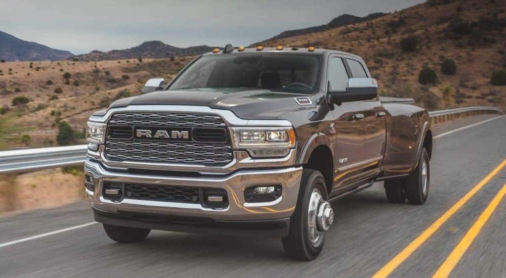 A black 2020 Ram 3500 Limited is shown driving down an empty road.