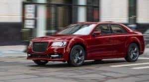 A red 2021 Chrysler 300 is driving on a city street after leaving Cincinnati Chrysler dealership.