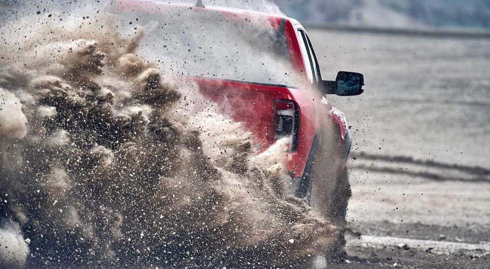 A red 2021 Ram 1500 TRX is shown from the rear kicking up dirt after leaving a Cincinnati Ram dealer.