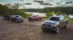 Three 2020 Ram 1500 trucks are parked on a dirt patch in front of a lake.