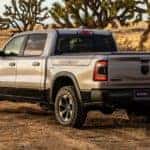 A silver 2021 Ram 1500 is shwon from the rear on a rural dirt road.