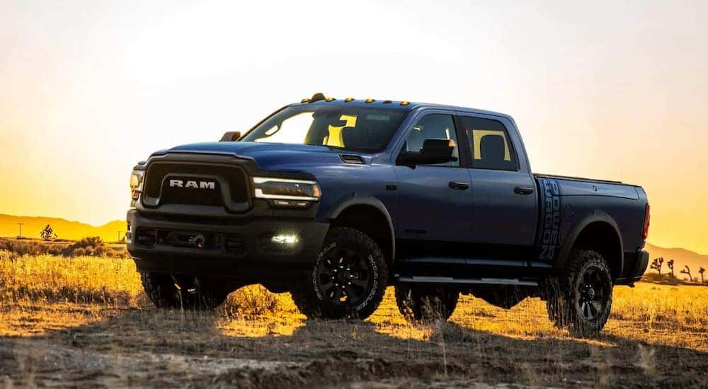 A blue 2021 Ram 2500 Power Wagon is off-roading at sunset.