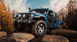 A blue 2021 Jeep Gladiator with no roof and doors is parked on rocks after leaving an Oakbrook Jeep dealership.
