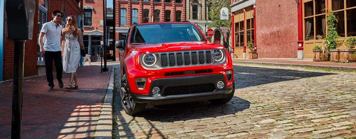 A red 2021 Jeep Renegade is parked in the city on a brick street.