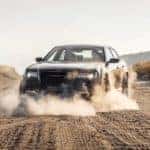 A grey 2021 Chrysler 300 is shown kicking up dust on a dirt road.