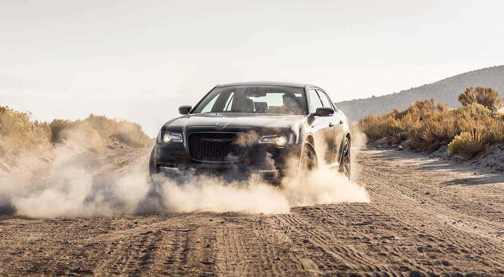A grey 2021 Chrysler 300 is shown kicking up dust on a dirt road.