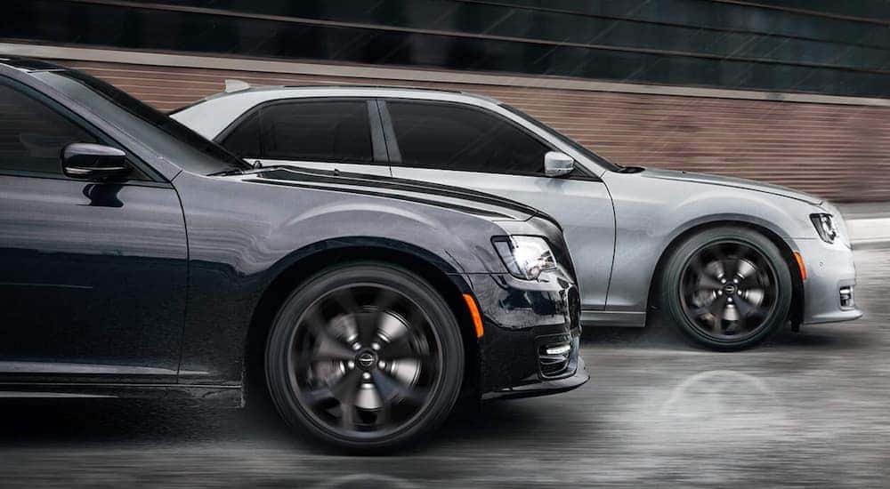 A black and silver 2021 Chrysler 300 are shown driving side by side in the rain.