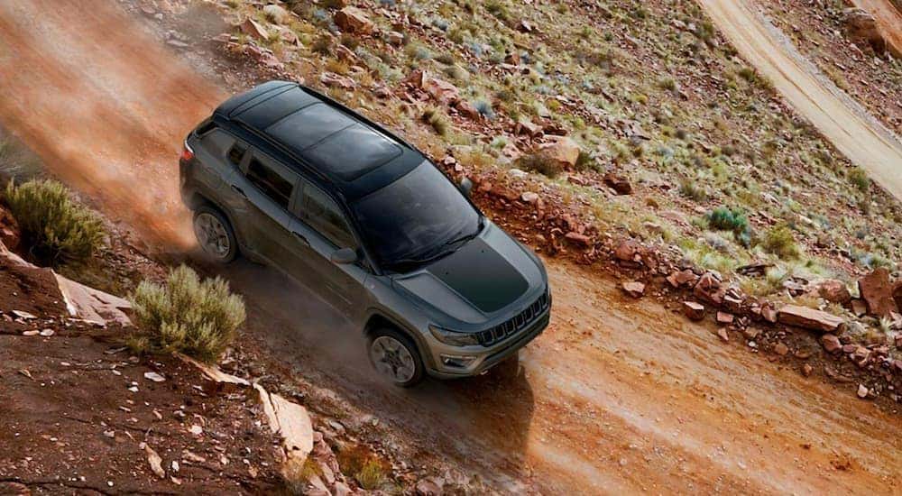 A grey 2019 Jeep Compass is shown from above driving on a dirt road after leaving a pre-owned Jeep dealer.