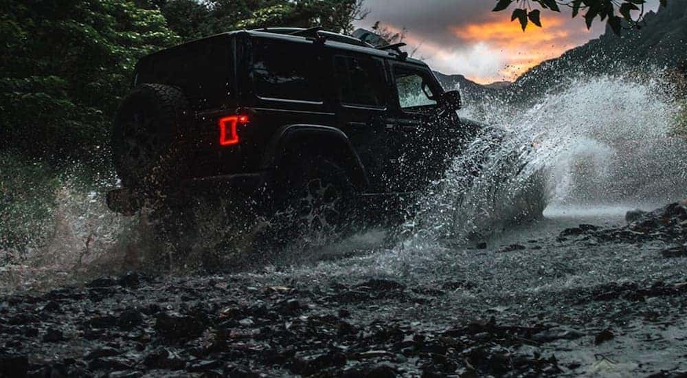 A black 2020 Jeep Wrangler Unlimited is shown driving through a river.
