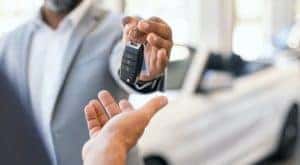 A salesman is passing a set of keys at a pre-owned Jeep dealer.