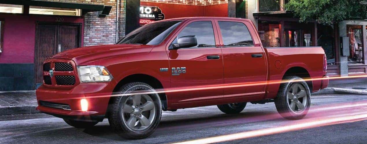 A red 2022 Ram 1500 is shown from the side parked on a city street.