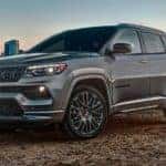 A grey 2022 Jeep Compass is shown across a lake from a city.