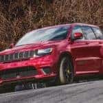 A red 2021 Jeep Grand Cherokee Trackhawk is shown driving on a race track from a low angle.