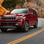 A red 2022 Wagoneer is shown driving on a winding road after visiting a Cincinnati Wagoneer dealer.