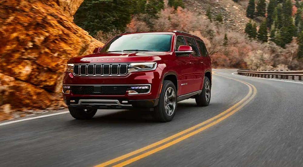 A red 2022 Wagoneer is shown driving on a winding road after visiting a Cincinnati Wagoneer dealer.