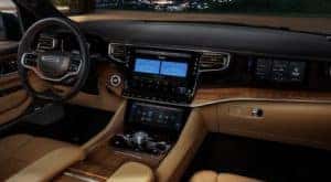 The black and tan interior of a 2022 Wagoneer shows the steering wheel and infotainment screen.