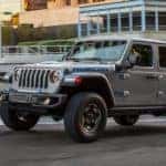 A grey 2021 Jeep Wrangler 4xe Rubicon Unlimited is shown driving through a city after visiting a Covington Jeep dealership.