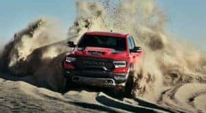 A red 2021 Ram 1500 TRX is shown from the front driving through a desert after leaving a Kentucky Ram TRX dealer.