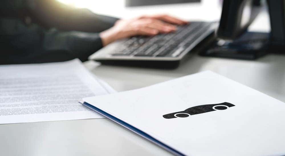A salesman is shown sitting at a desk with paperwork.