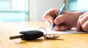 A person is shown filling out paperwork after searching 'how to sell your car.'
