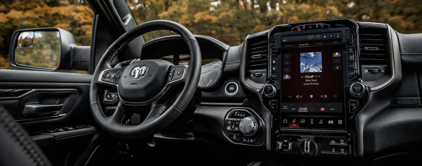 The black interior of a side by side shows the steering wheel and infotainment screen during a 2022 Ram 1500 vs 2022 Chevy Silverado 1500 comparison.