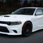 A white Certified Pre-Owned Dodge, a 2017 Dodge Charger is shown from the side driving on an open road.