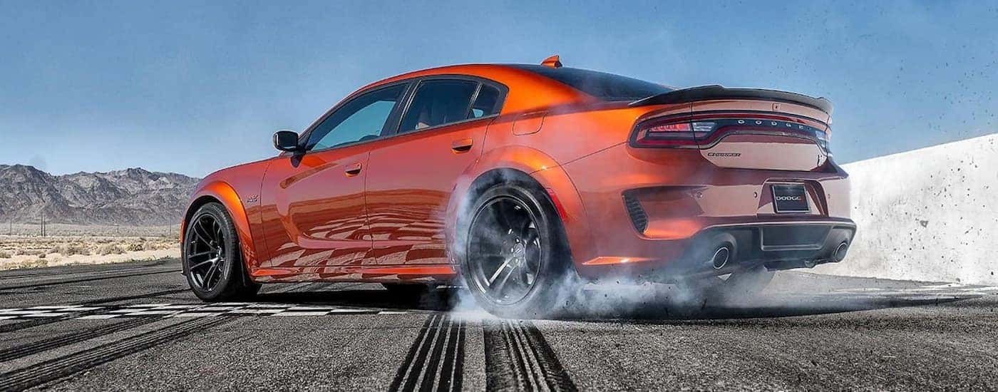 A popular Certified Pre-Owned Dodge, an orange 2020 Dodge Charger Scat Pack, is shown doing a burnou…